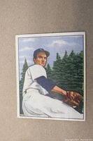 Front of 1950 Bowman Bob Cain baseball card showing pitcher in White Sox uniform in pitching stance with forest background.