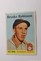 Front of 1958 Topps Brooks Robinson baseball card showing player portrait and team logo.