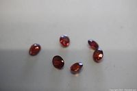 Photo showing six oval cut red garnet loose gems on neutral background
