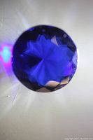 Top-down close-up view of round faceted blue sapphire showing star-like light reflections.
