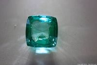 Front view of cushion-cut green tourmaline loose gemstone showing square shape and color