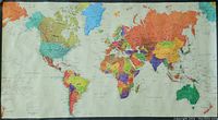 Front view of a large colorful political world map poster with countries and islands marked, measuring about 53 by 30 inches.