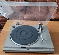 Front and top view of Onkyo CP1010A turntable with open clear dust cover showing tonearm, platter, and control buttons.