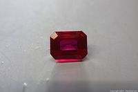 Front view of emerald cut loose ruby gemstone showing deep red color and faceting.