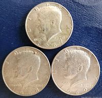 Obverse side of three Kennedy half dollar coins dated 1967, 1968, and 1969 with visible profile of JFK.