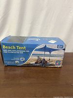 Photo of the closed box of the KMM beach tent showing the front with a photo of the tent in use on the beach.