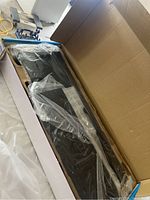 TV wall mount in original box wrapped in plastic, showing metal bracket and mount components.