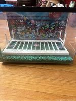 Front view of the fish tank showing the interior with football field and stadium background with cartoonish crowd.