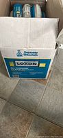 Open cardboard box showing 12 tubes of Sherwin Williams Loxon one-component acrylic hybrid masonry sealant in blue and white packaging.