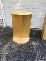 Front and center photo of the child-sized wooden coat and backpack rack with multiple pegs, shown on pavement in front of a garage door.