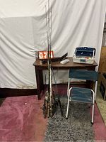 Full view of fishing rods leaning against a table, tackle box on table, and small folding chair in front.
