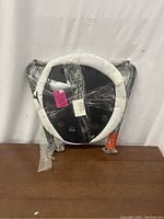 Parts for metal round side table wrapped in plastic including a round tabletop with floral cutouts and a white protective ring.