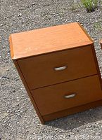 Wooden 2-drawer night stand exterior showing two silver drawer handles, light brown wood finish with minor surface wear.