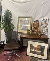 Shows office chair, desk, framed wall art, decorative planter, tall artificial plant and metal flower wall art.