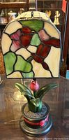 Close-up of stained glass lamp showing colorful bird and floral motifs