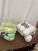 Image showing two bags of yarn skeins, one with white yarn and the other with multi-colored pastel yarns