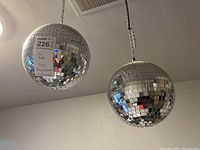 Two disco balls hanging from ceiling with labels showing lot number and notes."