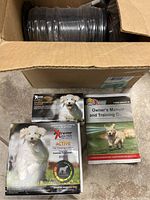 View of Extreme Dog Fence EAF100 Active pet fencing system boxes and owner’s manuals with instructional covers featuring dogs.