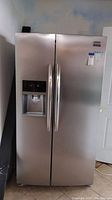 Full front view of stainless steel side-by-side refrigerator showing both doors and dispenser