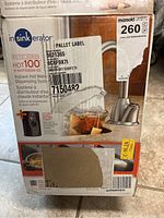 Front of the original packaging showing the InSinkErator Hot100 hot water dispensing system with stainless steel faucet and branding details.
