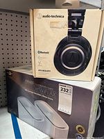 Photo of the ASUS ZenWiFi AX AX6600 system and Audio-Technica ATH-M50xBT2 headphones boxed together, showing front of both product boxes.