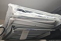 Photo of stacked metal ramps on a shelf, one wrapped with foam and plastic.