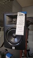 Front view of JBL speaker with 15 inch woofer and horn tweeter, mounted on stand, with MaxSold tag