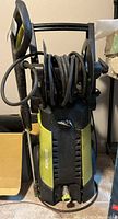 Front view of Sun Joe electric pressure washer unit with hose wrapped on reel and green/black color scheme