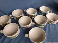 9 white ceramic soup bowls with handles, arranged in multiple rows, each decorated with colorful Campbell's Kids illustrations around the exterior.