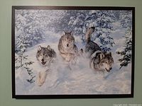 Full view of canvas print showing three wolves running in snowy forest environment, framed on wall.
