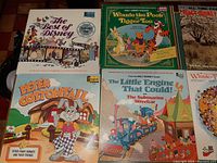 Eight kids vinyl records including two Disney read along book sets, displayed on a brown wood surface.