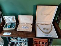 Full view of three separate boxes of jewelry with lot numbers 30, 31, and 32. Lot 32 contains the Fifth Avenue Collection jewelry set in a white case.