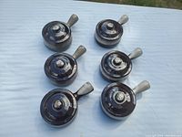 Six lidded French onion soup bowls arranged on a white cloth, top view showing the lids and handles.