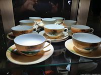 Full display of the ten-piece tea set featuring five cups and five saucers arranged in a glass cabinet.