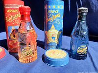Front view of both Versace Red Jeans and Blue Jeans cologne bottles with their original tins, showing packaging and branding details.