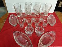 Set of 17 vintage ice cream parlor glasses and dishes, arranged in three rows featuring varying sizes and types of clear ribbed glassware including milkshake glasses, sundae glasses, pedestal bowls, and banana split dishes.