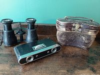 Two pairs of opera glasses and an additional folding pair, with original leatherette and red-lined cases.