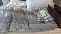 King size bed linens laid out on bed showing duvet cover, pillows and folded sheets