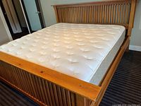 Wooden slatted bed frame with headboard and mattress, angled side view