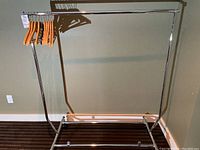 Full view of the metal frame clothing rack with wooden hangers on the bar, showing the structure and size.