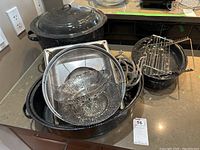 Photo showing large enameled oval roasting pan with several smaller pots inside, including a collapsible metal steamer basket and metal racks.