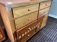 Front-right angled view showing eight drawers and round wooden knobs