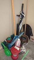 Full view of all items clustered together showing shovel, umbrella, bike pump, portable light, gas container, and watering can among others.