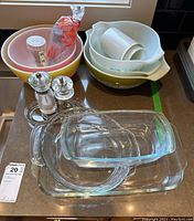 Pyrex mixing bowls, glass baking dishes, salt and pepper grinders on clear tray