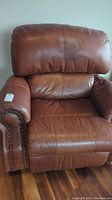 Front view of brown leather recliner chair showing cushioned seat and backrest.