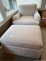 Overall photo of beige lounge chair with matching ottoman in natural light near windows