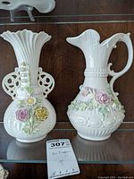 Front view of two Belleek Aberdeen porcelain pieces sitting side by side on a glass shelf, showing floral designs and shape details.