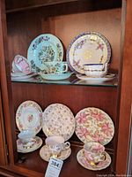 Overall view of display cabinet showing all six tea cup, saucer and plate sets