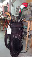 Full view of the black TaylorMade golf bag with clubs inside in a workshop setting