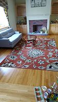 Full view of the floral pattern rug in living room setting with couch and fireplace